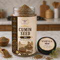 A jar of SSRYJA Cumin Seed spice mix with its lid placed beside it on a kitchen countertop. The clear jar shows the cumin seeds inside, and the label reads 'Cumin Seed' with additional text and illustrations.