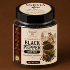 A 50g jar of SSRYJA Premium Spices Black Pepper, featuring a cream-colored label with illustrations of a woman harvesting black peppercorns, a wooden bowl of peppercorns, and a black lid, set against a solid brown background.